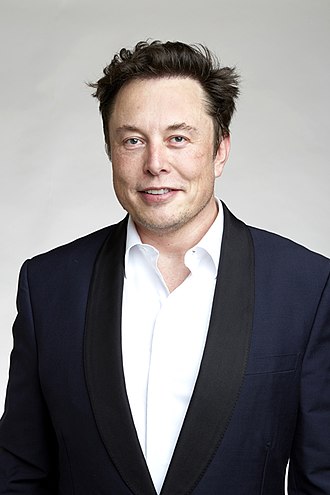 Portrait of 49 year old man with short brown hair and brown eyes, smiling. Wearing open white shirt with a dark jacket.
